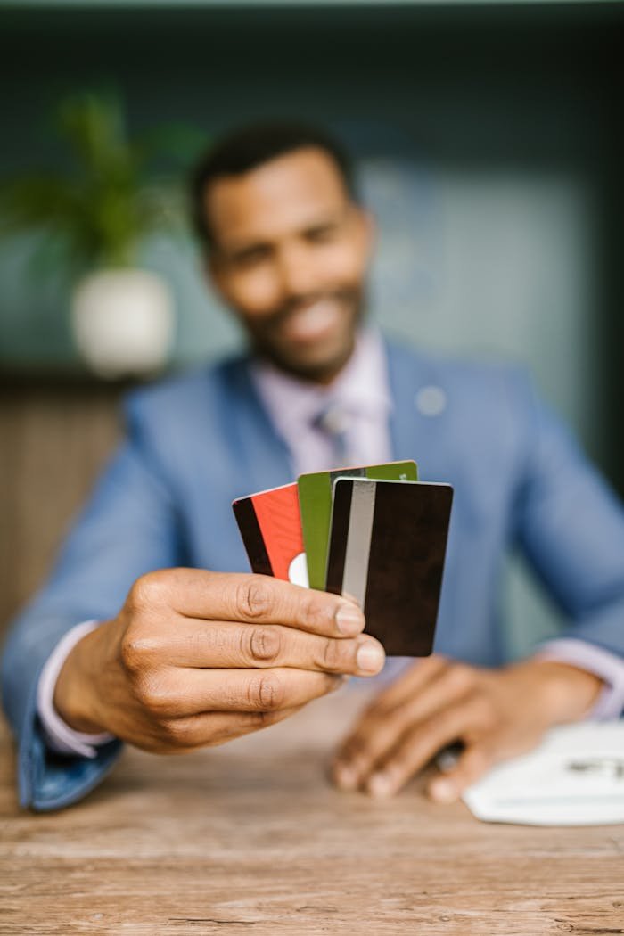 Professional man in suit holding multiple credit cards, emphasizing finance and business concept.